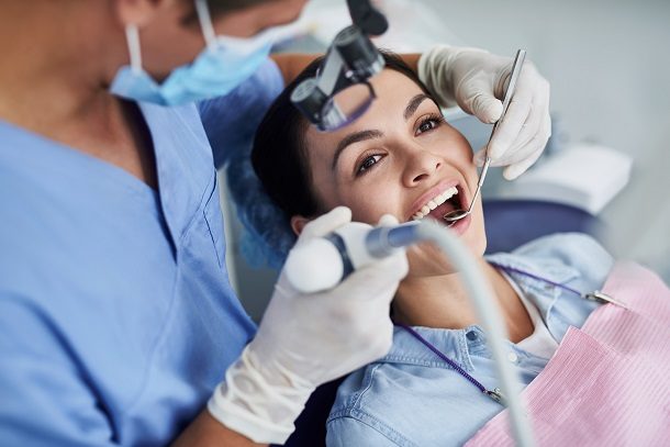 Frau sitzt beim Zahnarzt und bekommt eine Prophylaxe